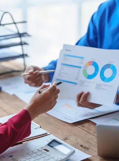 Primer plano de manos analizando gráficos financieros, resaltando la importancia de datos para cumplir con las normas ISO.