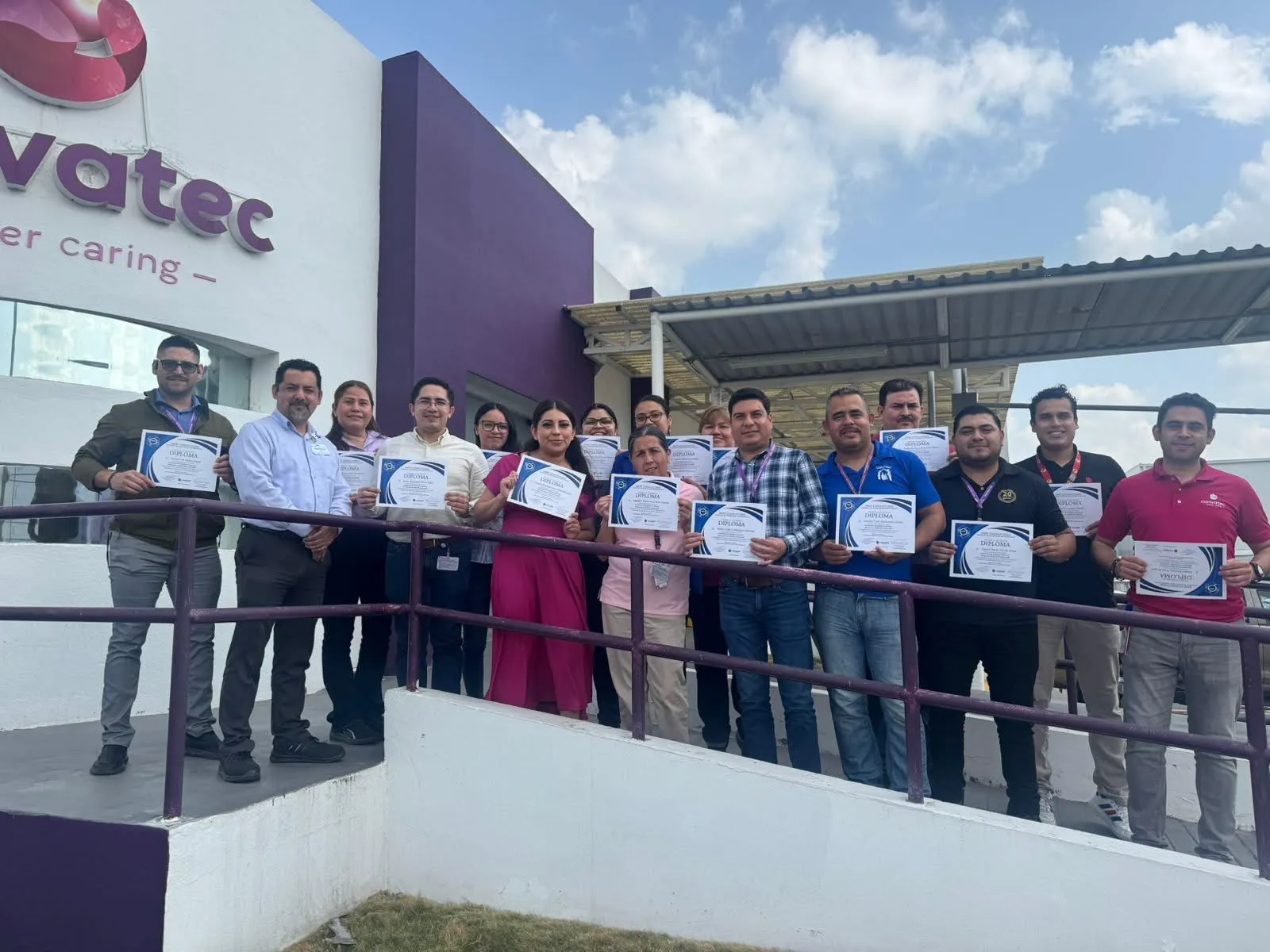 Un grupo diverso de empleados de una empresa, sonríe y posa con certificados después de una capacitación exitosa.