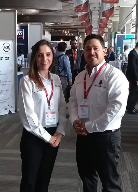 Dos trabajadores de consultoría empresarial sonriendo, usando camisas blancas en un evento o convención de negocios.<br />
