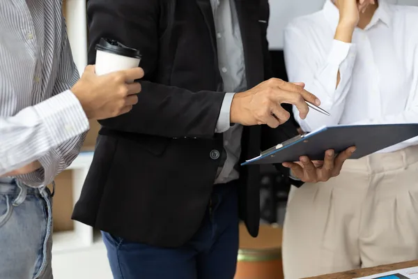 Profesional de traje con portapapeles explica checklist de cumplimiento a equipo como experto consultor iso.