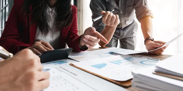 Manos de equipo y consultor iso analizando gráficos y datos con calculadora en reunión estratégica de negocios