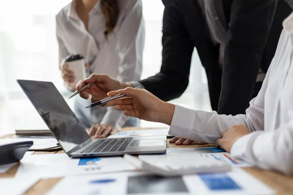 Grupo de trabajo analiza datos en pantalla de laptop señalados por un consultor iso durante auditoría digital.