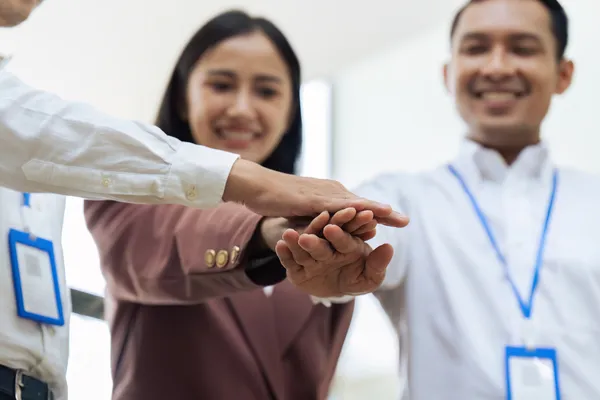 Fotografía de un grupo de personas juntando sus manos en el centro en muestra de compromiso con la ISO 9001.
