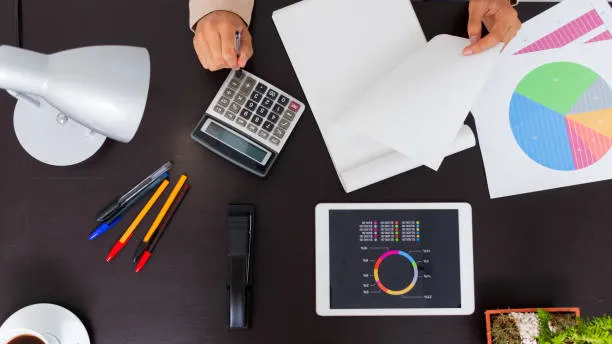 Calculadora, documentos y gráficas utilizados para evaluar el costo certificación ISO 9001 en una empresa